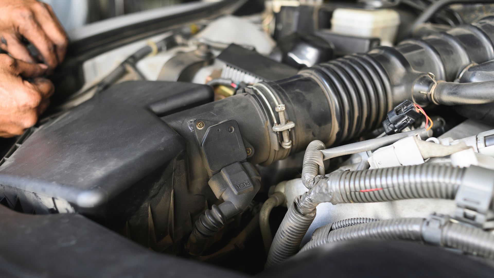 a close up of a person working on a car engine.|a man is working on a car engine.