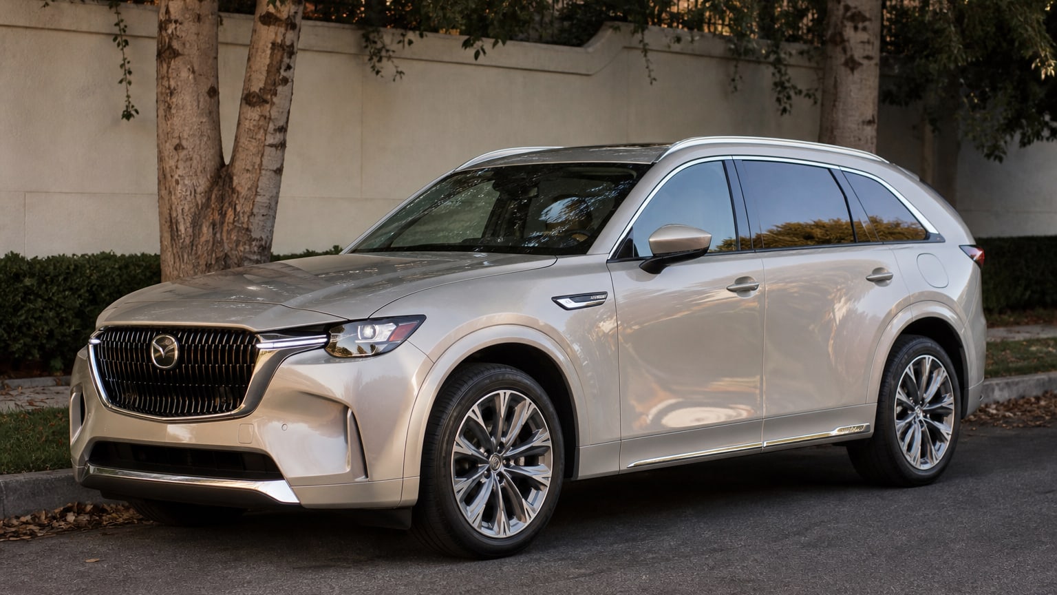 A silver 2026 Mazda CX-90 parked on a tree-lined street.