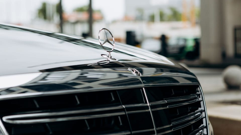 a close up of the front grill of a car.|a row of parked cars sitting next to each other.|a black mercedes benz benz benz benz benz benz benz benz benz benz benz benz benz.