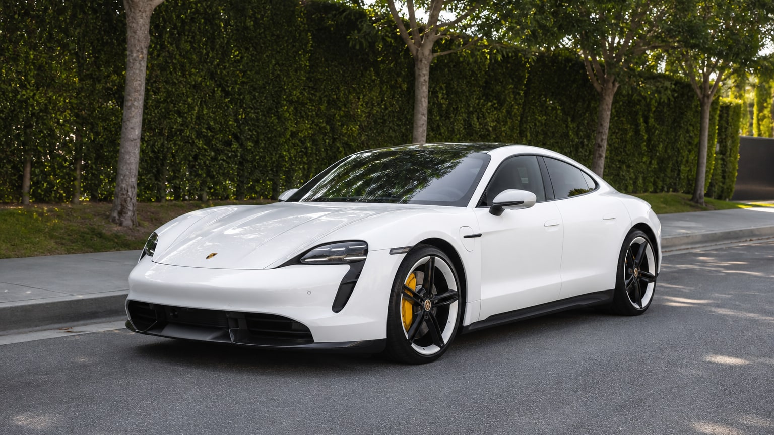 A cleaner later-model Porsche Taycan on a quiet road.