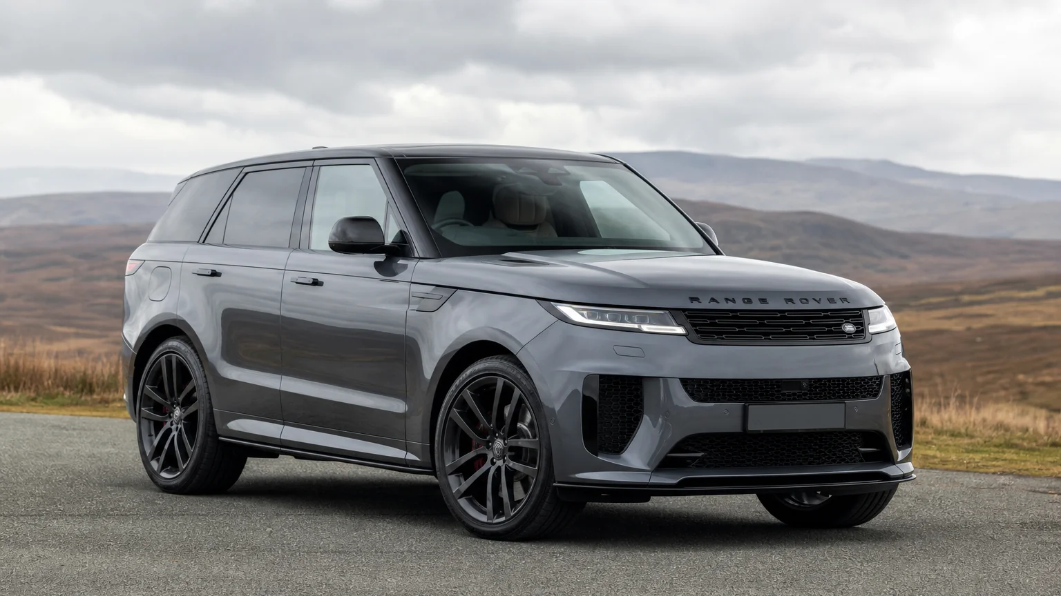 A Range Rover Sport performance SUV, three-quarter front view, parked on a quiet street.