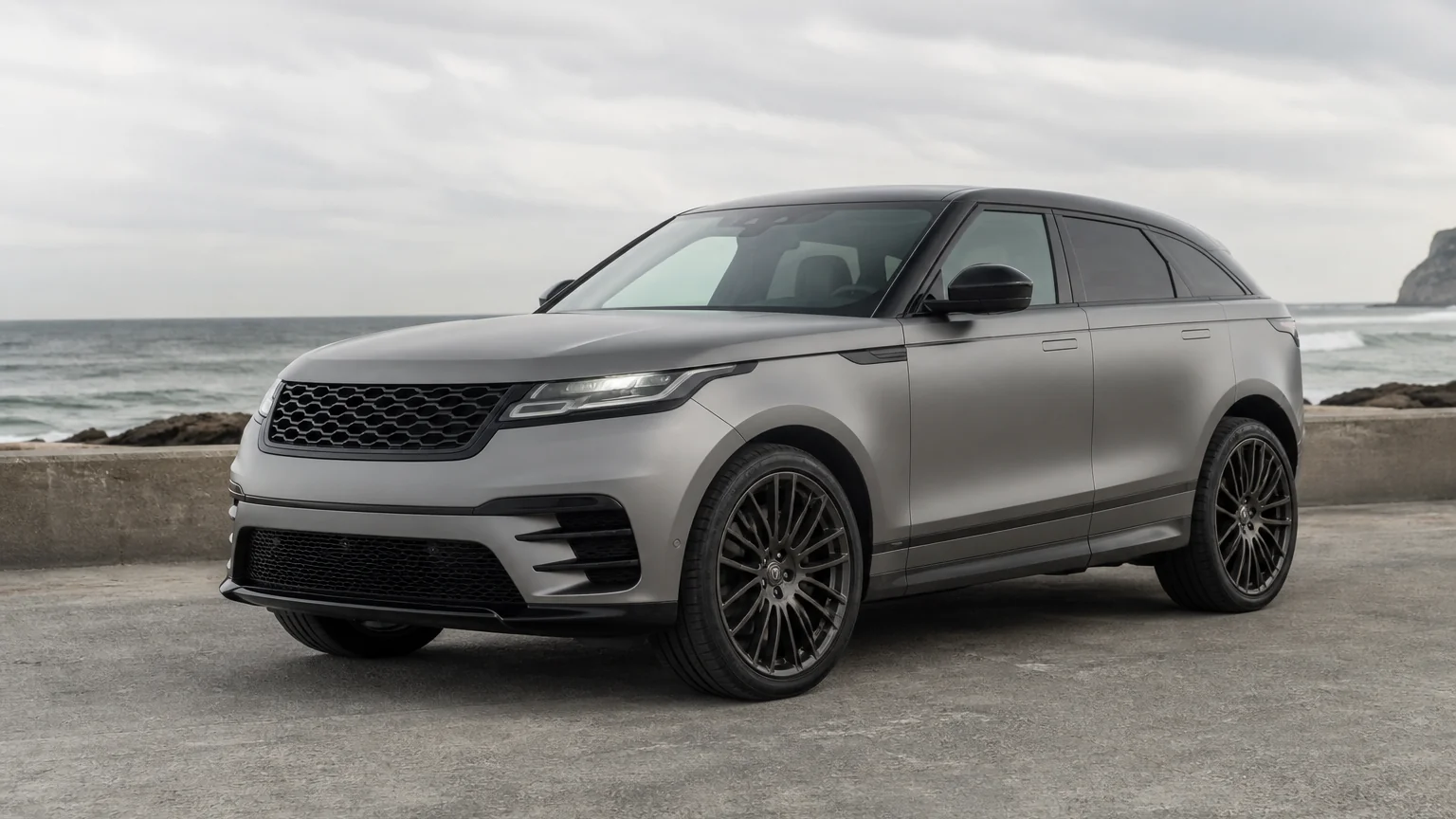 A Range Rover Velar midsize luxury SUV, three-quarter front view, parked on a quiet street.