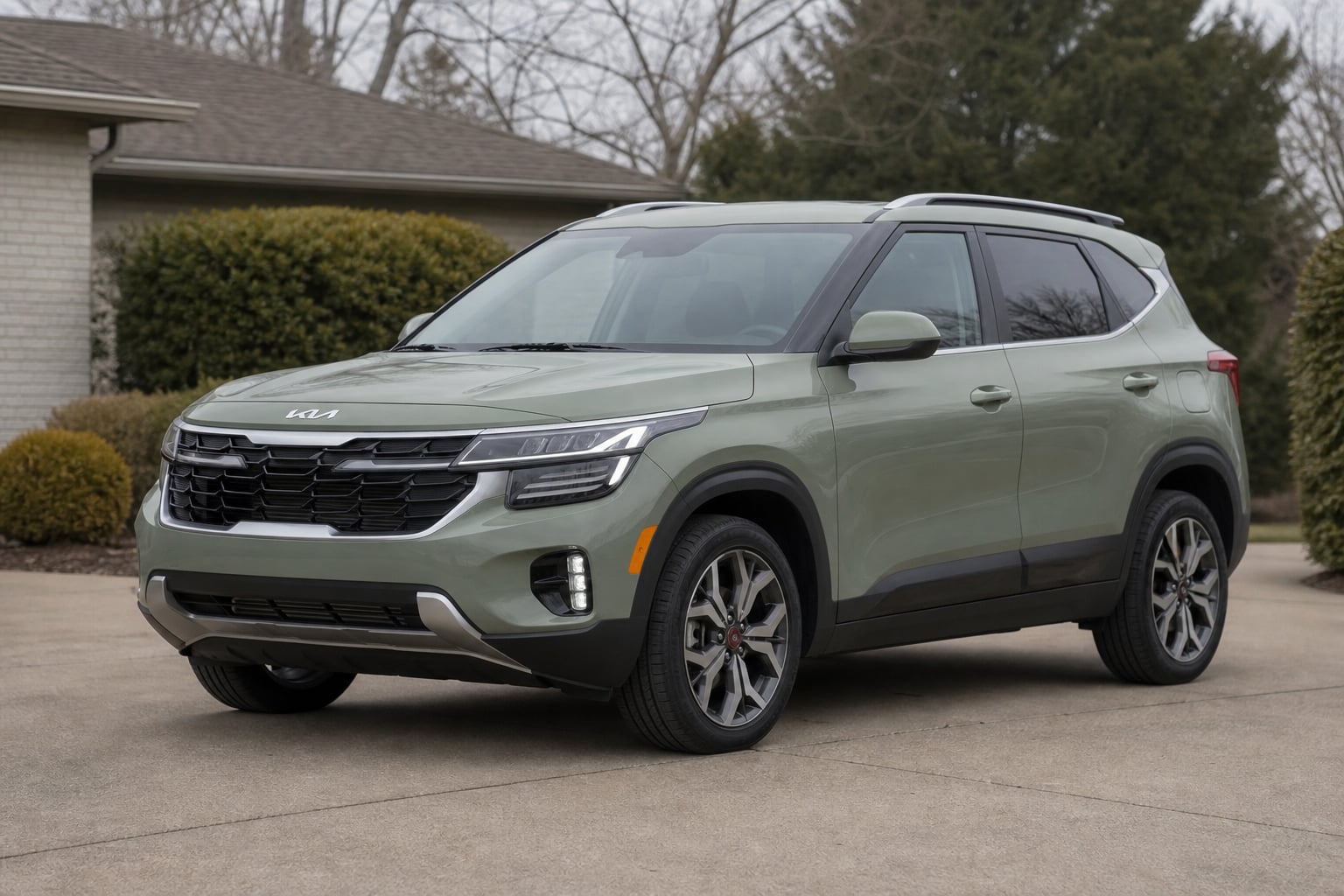 Sage green Kia Seltos compact SUV in a suburban driveway