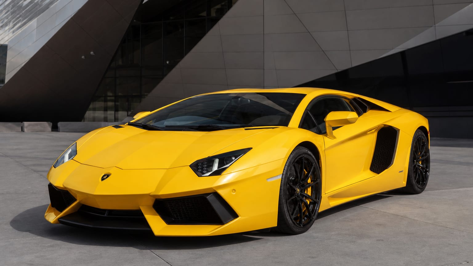 Yellow Lamborghini Aventador parked outside a contemporary building
