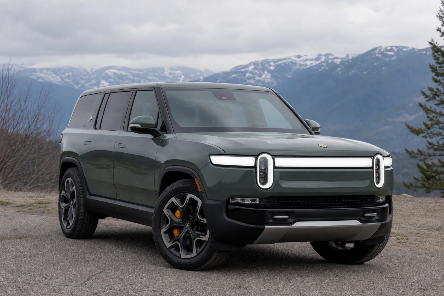Green Rivian-style electric crossover parked on a scenic overlook