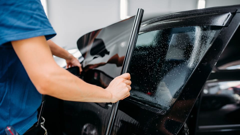 a man waxing a car in a garage.|two hands reaching out of a car window.