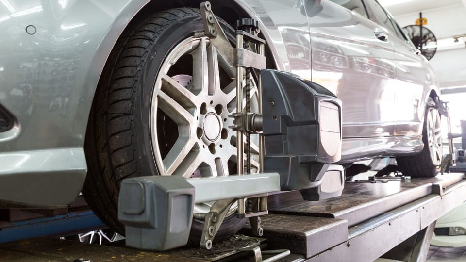 a car being worked on by a mechanic.|a person with a glove on their hand is changing the tire of a blue car.
