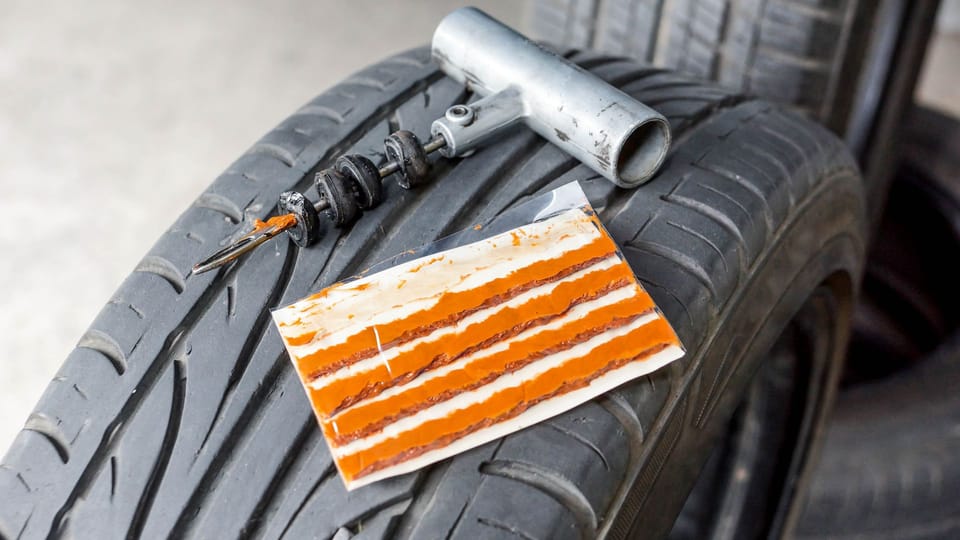 an orange and white piece of paper sitting on top of a tire.|a close up of a tire with a wrench.