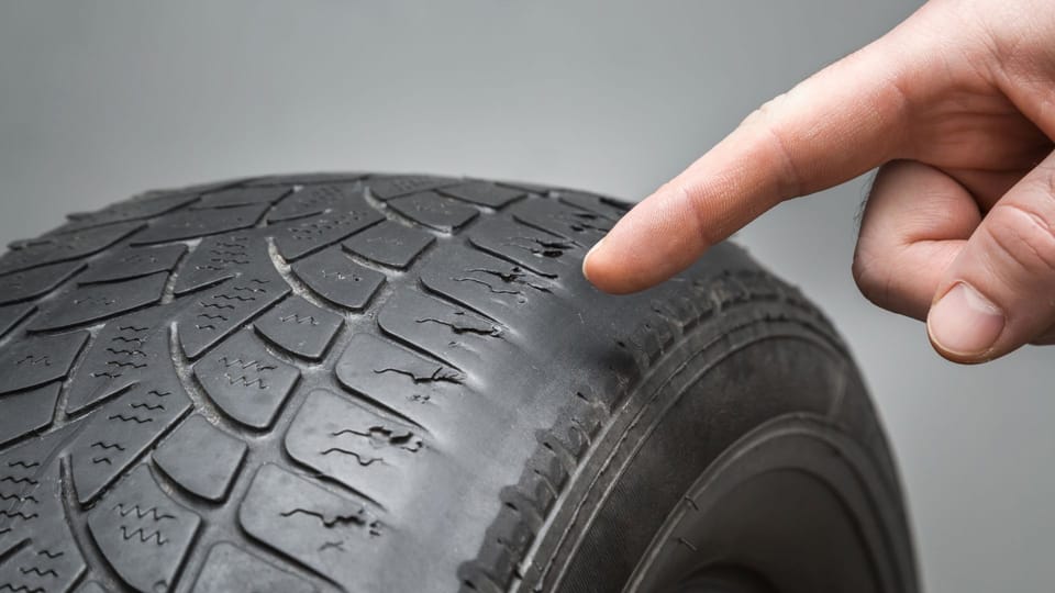a hand pointing at a tire on a gray background.|a close up of a metal object with a wrench.|a man is changing the tire of a car.
