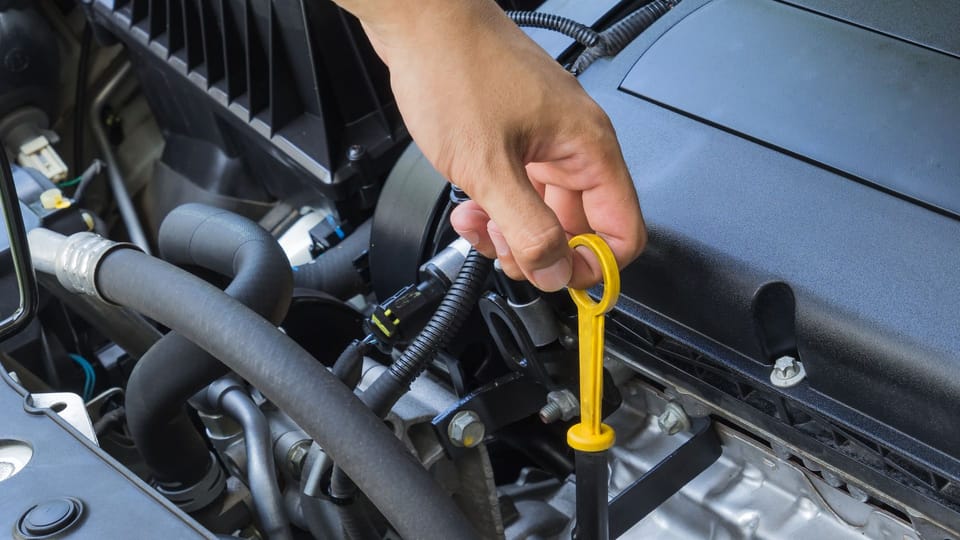 a person holding a wrench in front of a car engine.|a car with its hood open on the side of the road.