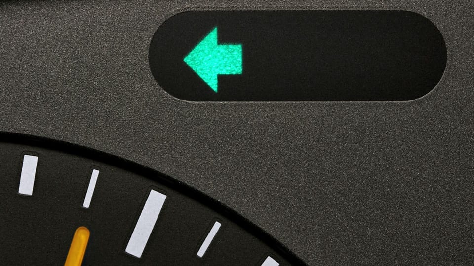 a person holding a remote control in a car.|a close up of a clock with a green arrow on it.|a man is working on a car's engine.|a person holding a small object in their hand.