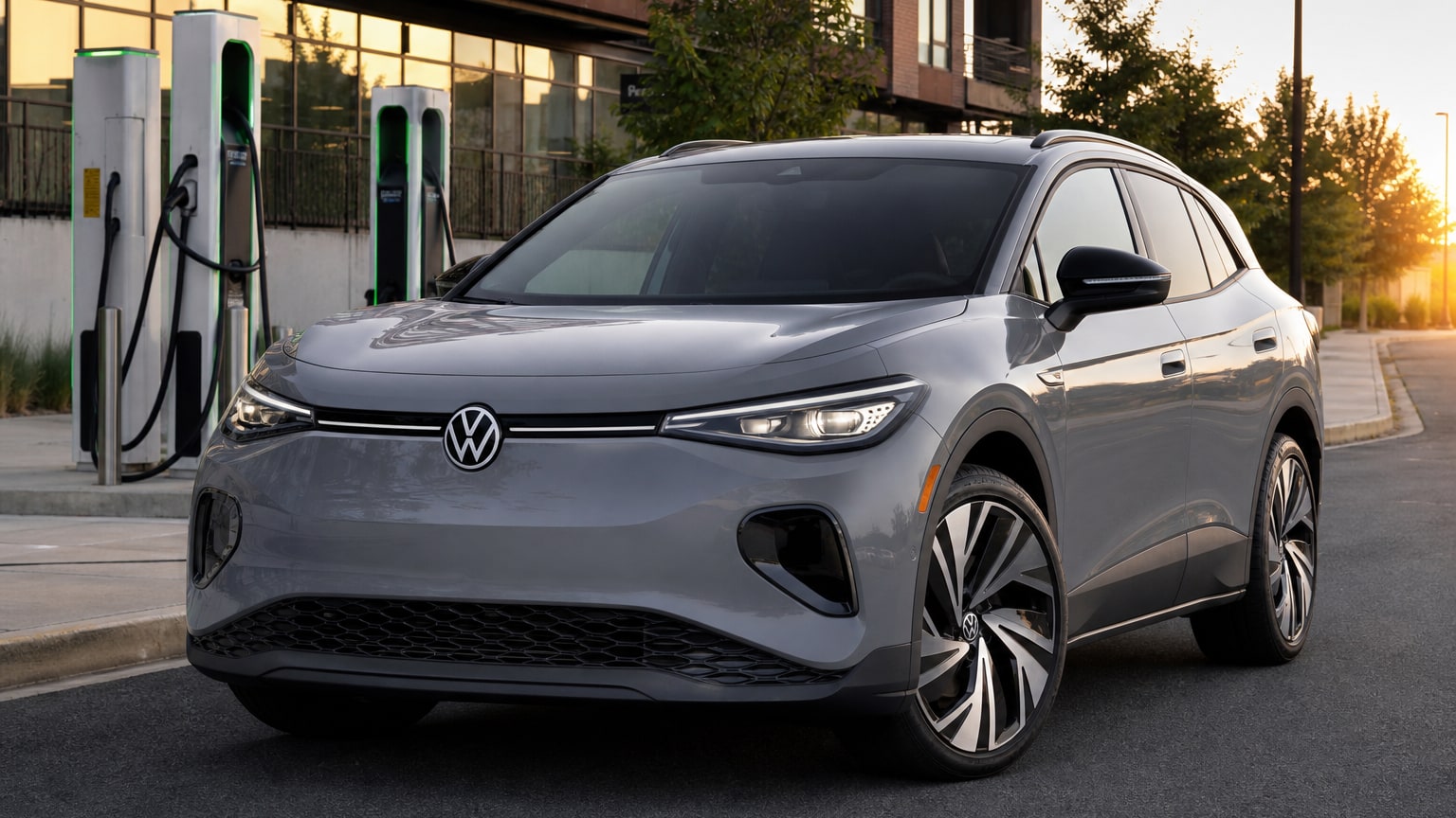 A gray 2025 Volkswagen ID.4 on a city street near EV chargers.