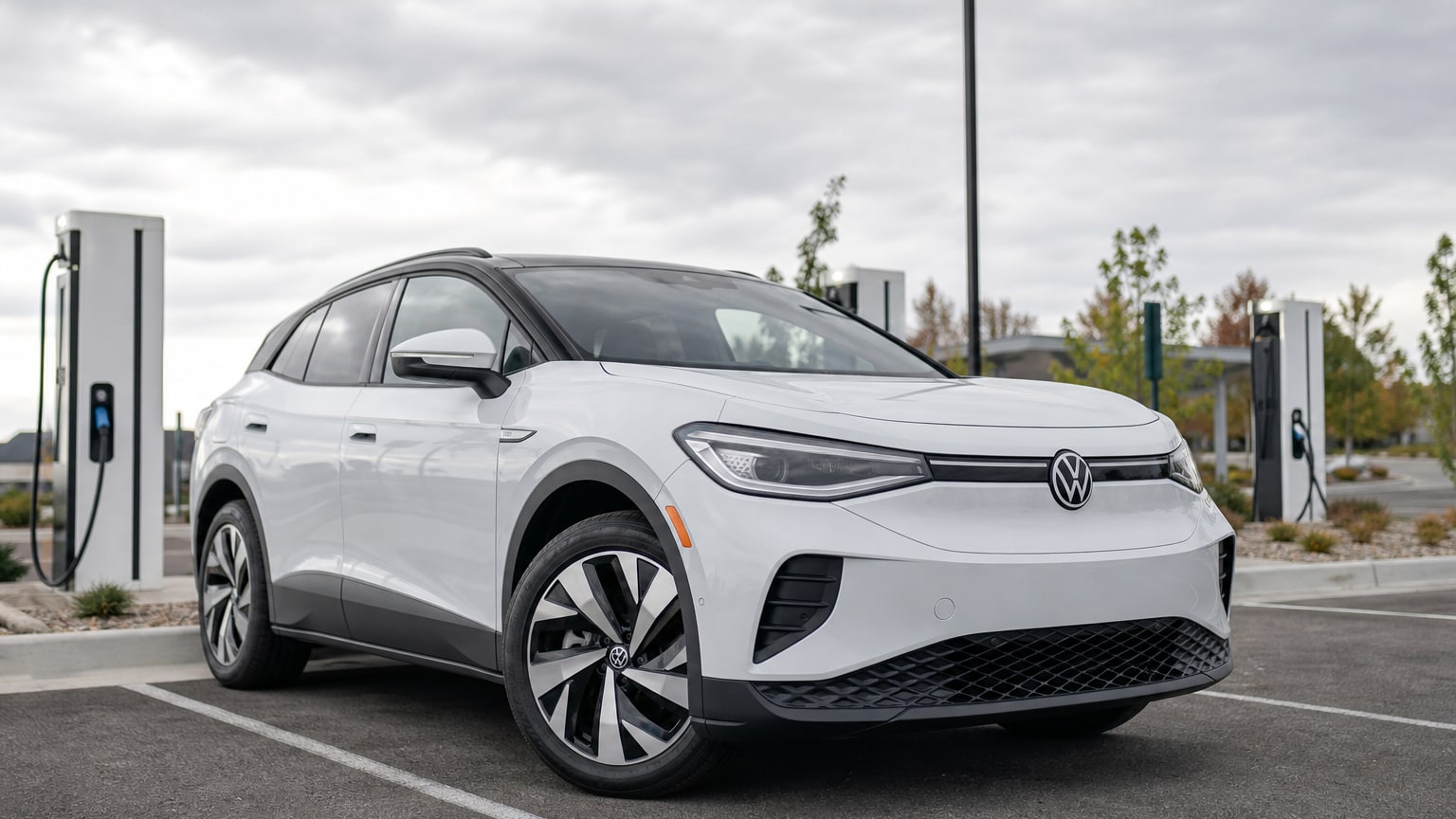 A white Volkswagen ID.4 electric SUV parked at a public charging plaza.