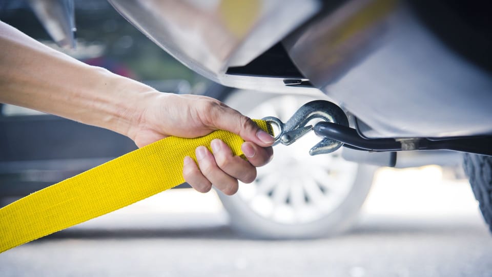 a person holding a wrench to a yellow hose.|the dashboard of a car with various gauges.